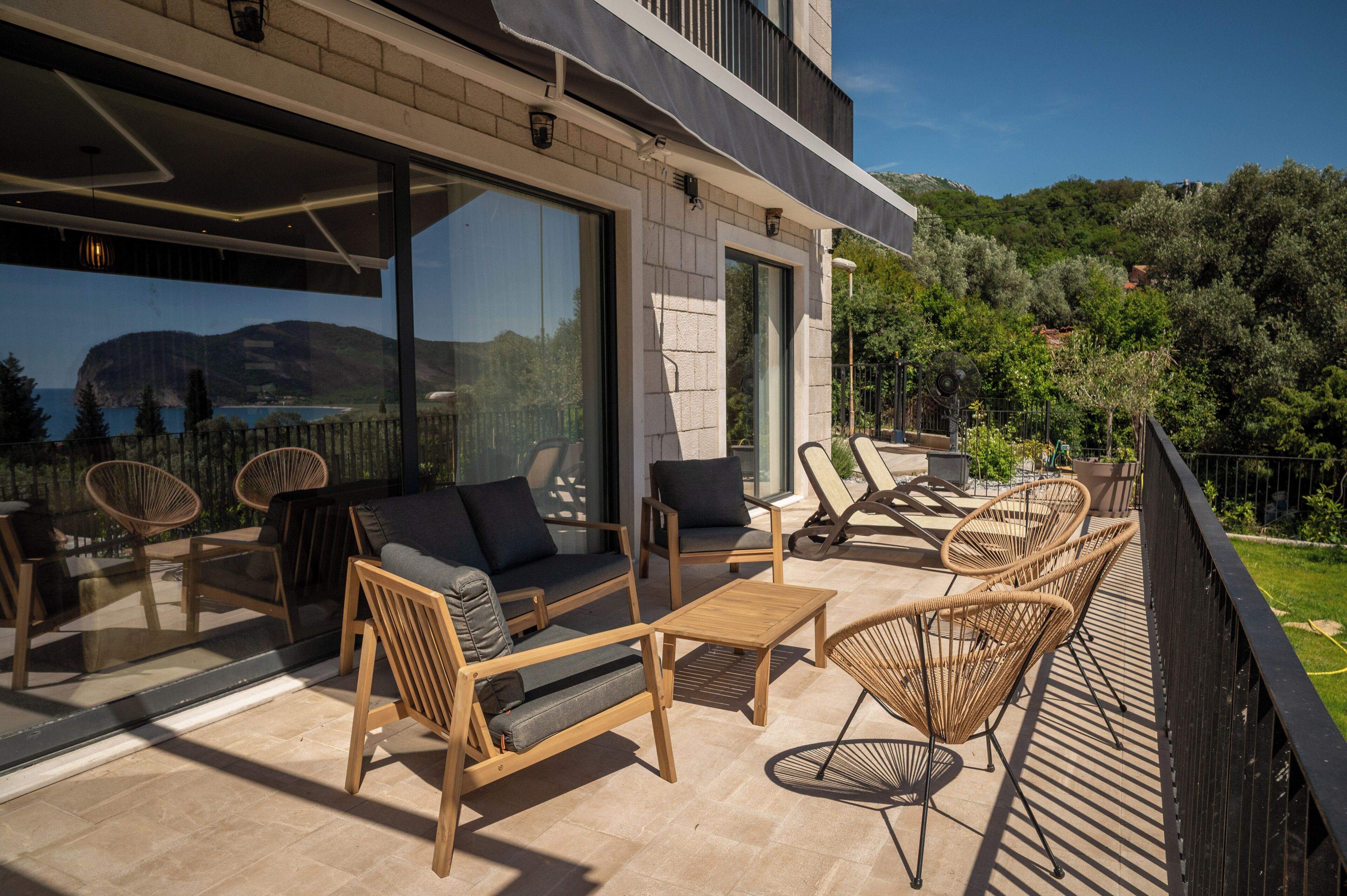 Un patio extérieur moderne avec un canapé, des fauteuils et une table.