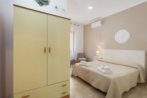 Una camera da letto con un letto, un armadio, un comodino e un condizionatore d'aria a parete.