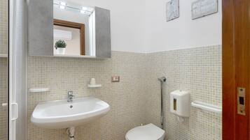 Een badkamer met een wastafel, toilet en handdroger.
