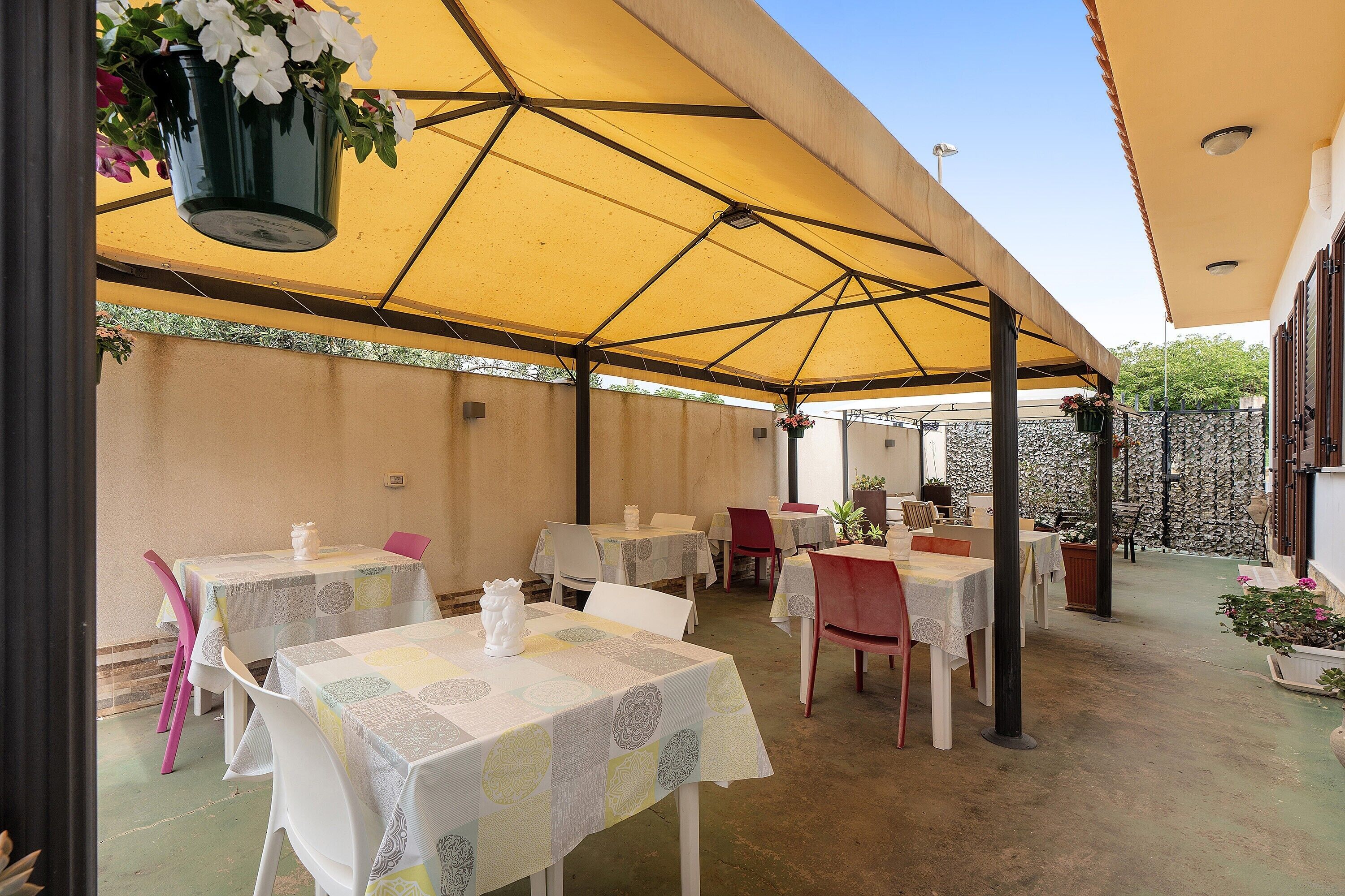 Un área de comedor al aire libre con mesas y sillas bajo un toldo grande.