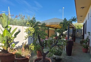 A courtyard with potted plants, outdoor seating, and a covered area. - Room 'Demetra Malophoros - 16' with Shared Terrace, Wi-Fi and Air Conditioning (Marinella)