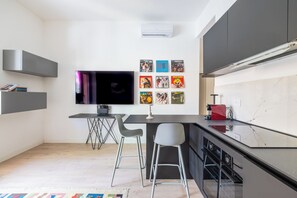 A modern kitchen with a flat-screen TV, bar stools, and a marble countertop. - Piazzale Clodio Apartment (Roma)