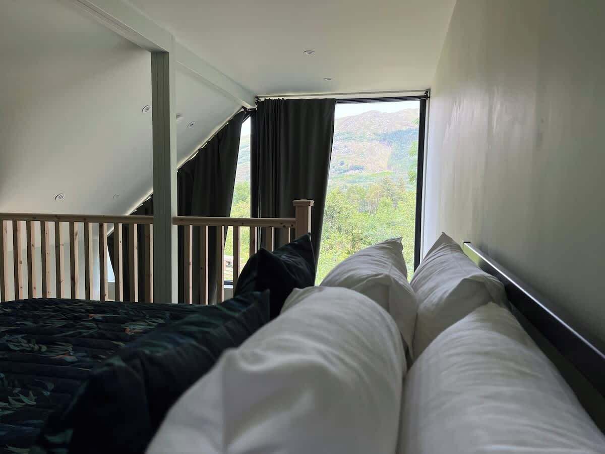 Une chambre à coucher avec un lit, une fenêtre avec des rideaux et une vue sur la verdure.