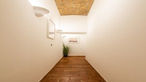 A hallway with a brick floor, white walls, and a stone ceiling. - Lovely 1-bedroom apartment with AC in vibrant Roma (Roma)