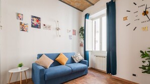 A living room with a blue sofa, a small side table, and a radiator. - Lovely 1-bedroom apartment with AC in vibrant Roma (Roma)
