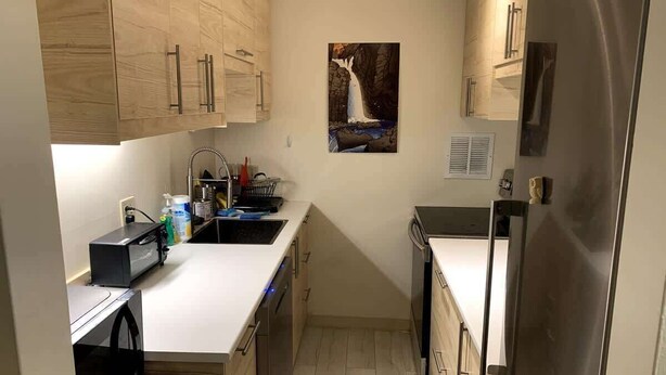 A compact kitchen with wooden cabinets, a dishwasher, a microwave, and a sink.