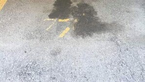 A parking area with a yellow line and a black stain on the floor.