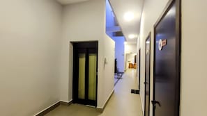 A hallway with a door on the left and a door on the right, both with handles and a sign above the right door.