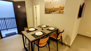 A dining area with a table set for two, two chairs, a door with a number, and a wall-mounted TV. - Airport Residence (Guarulhos)