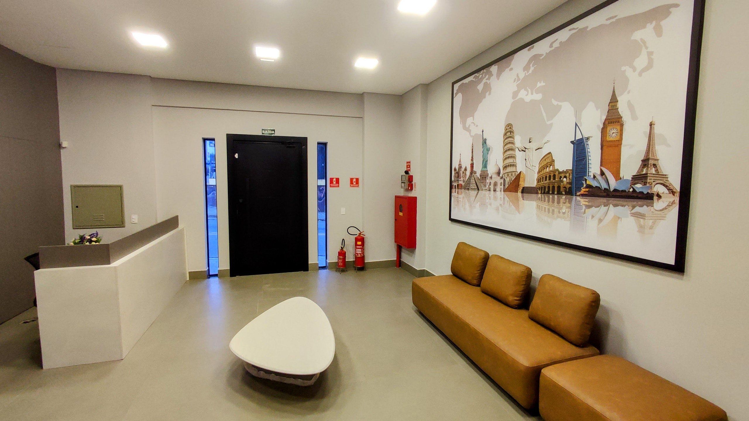 A reception area with a desk, a couch, a fire extinguisher, and a world map mural.