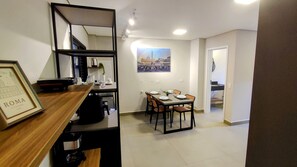 A dining area with a table set for four, a framed picture of Rome, and a kitchen area with a sink and cabinets.