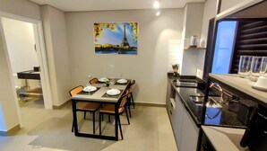 A modern kitchen with a dining area, a painting of the Eiffel Tower, and a view of the city. - Airport Residence (Guarulhos)