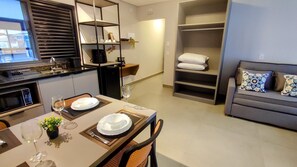 A modern kitchen with a dining area, a built-in bookshelf, and a grey sofa with patterned cushions. - Airport Residence (Guarulhos)