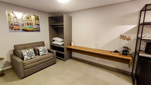 A modern living room with a sofa, pillows, a coffee machine, and a wall-mounted shelf.