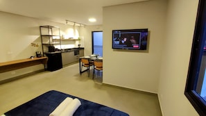 A compact hotel room with a bed, a small kitchenette, a dining area, and a TV mounted on the wall. - Airport Residence (Guarulhos)