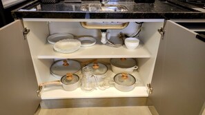 A kitchen with a built-in sink, white cabinets, and various kitchenware including pots, pans, and dishes. - Airport Residence (Guarulhos)