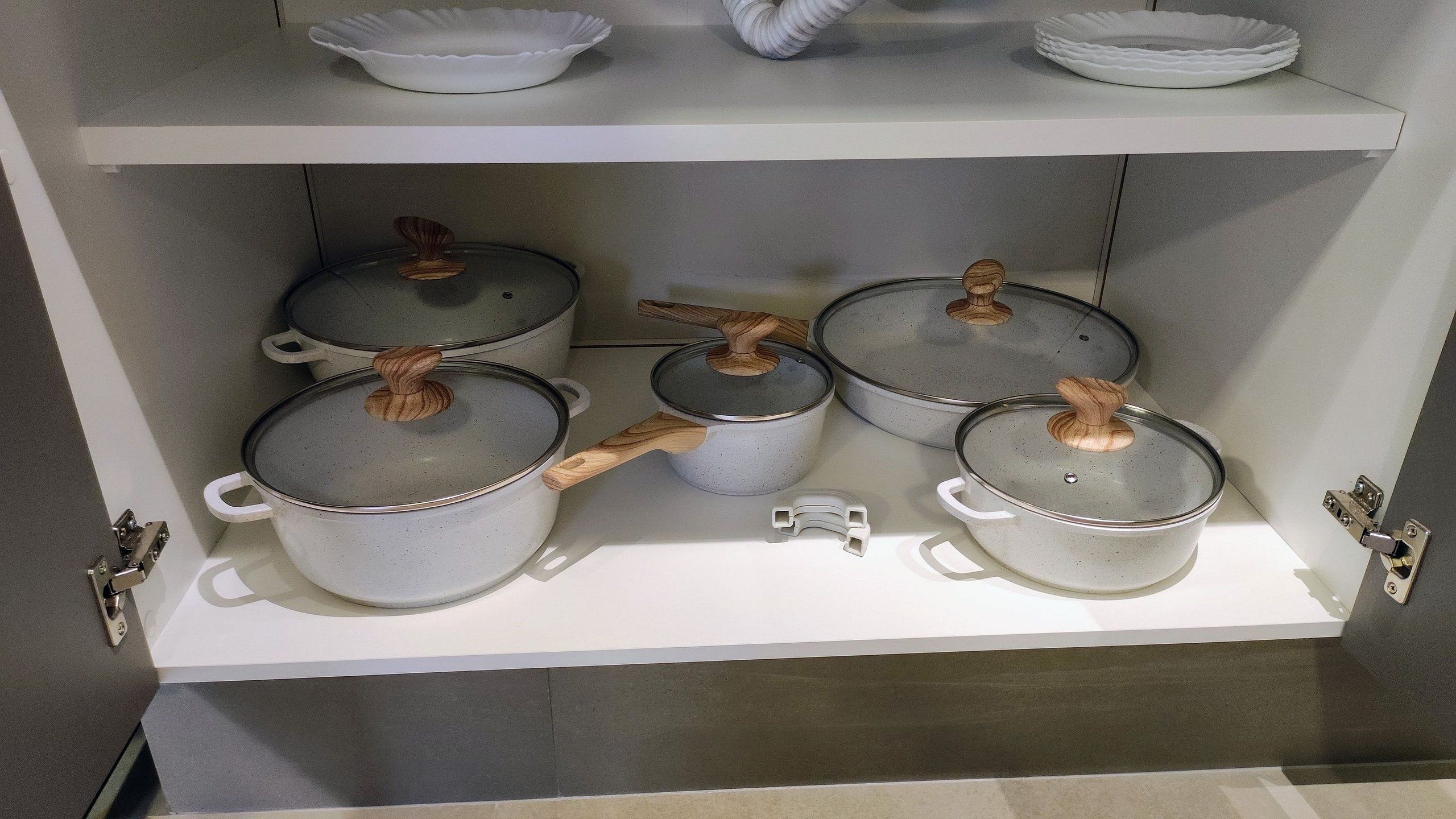 A kitchen shelf with four pots and a small utensil holder.