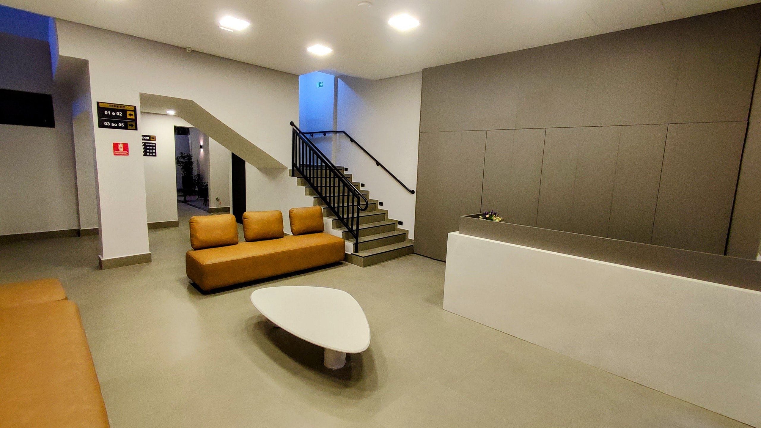 Un hall d’entrée moderne avec un escalier, un canapé et un comptoir d’accueil.