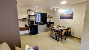 Ett kompakt bostadsutrymme med ett litet kök, en matplats och en tavla som hänger på väggen.
