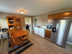 Eine moderne Küche mit Holzschränken, einem Edelstahlkühlschrank, einem Einbauofen und einem Esstisch mit Stühlen.