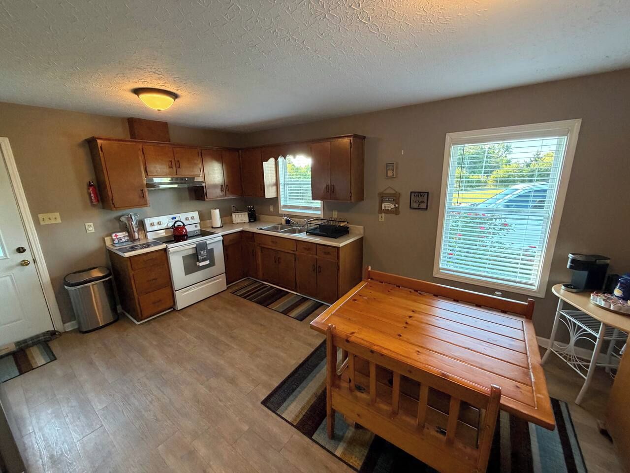 Une cuisine de taille réduite, avec des meubles de rangement en bois, une cuisinière et une table à manger.