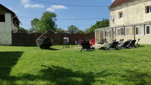 Une cour arrière verdoyante avec une clôture en bois, un barbecue et plusieurs chaises longues.