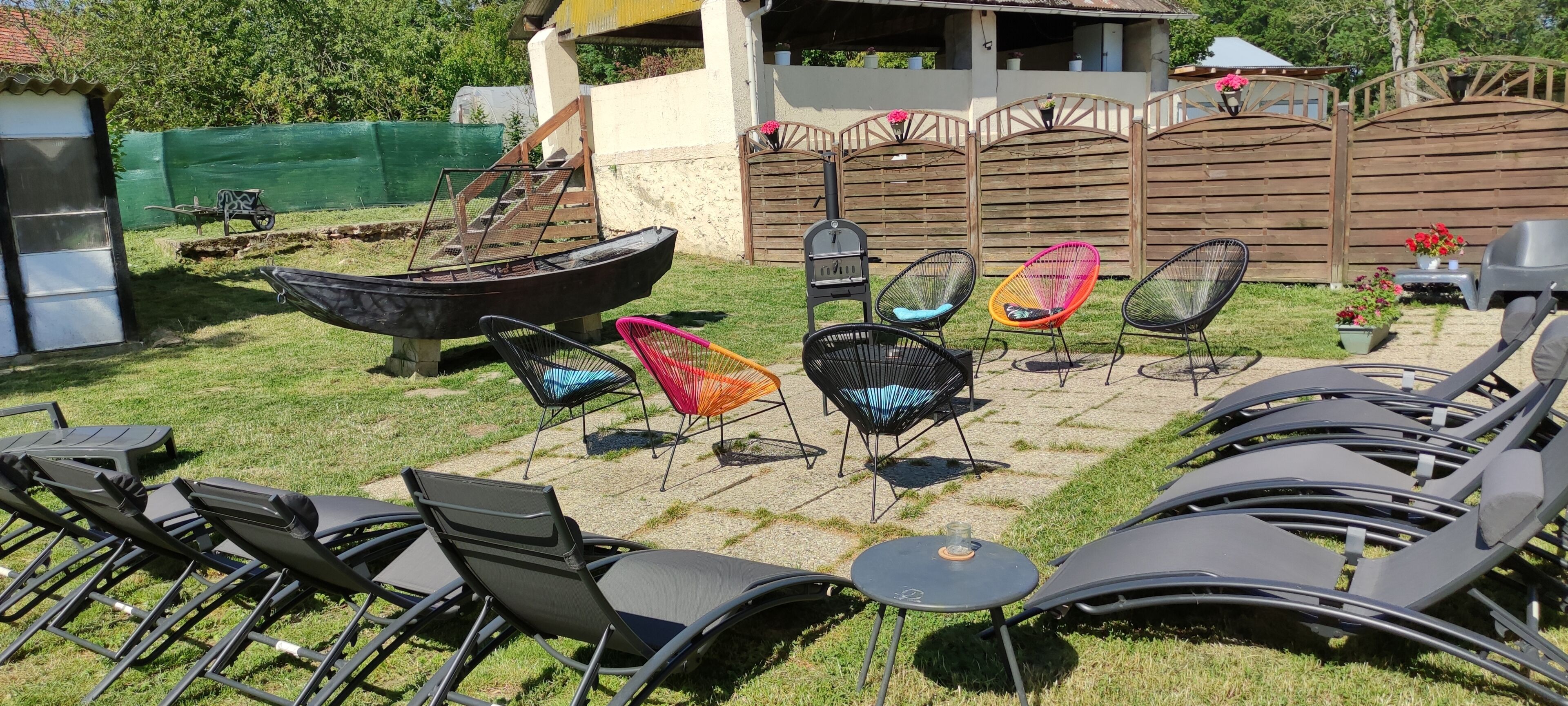 Um pátio com área externa, incluindo espreguiçadeiras, cadeiras, uma mesa pequena e um barco.