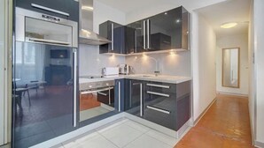 A modern kitchen with dark cabinetry, a built-in oven, and a countertop with a coffee maker.