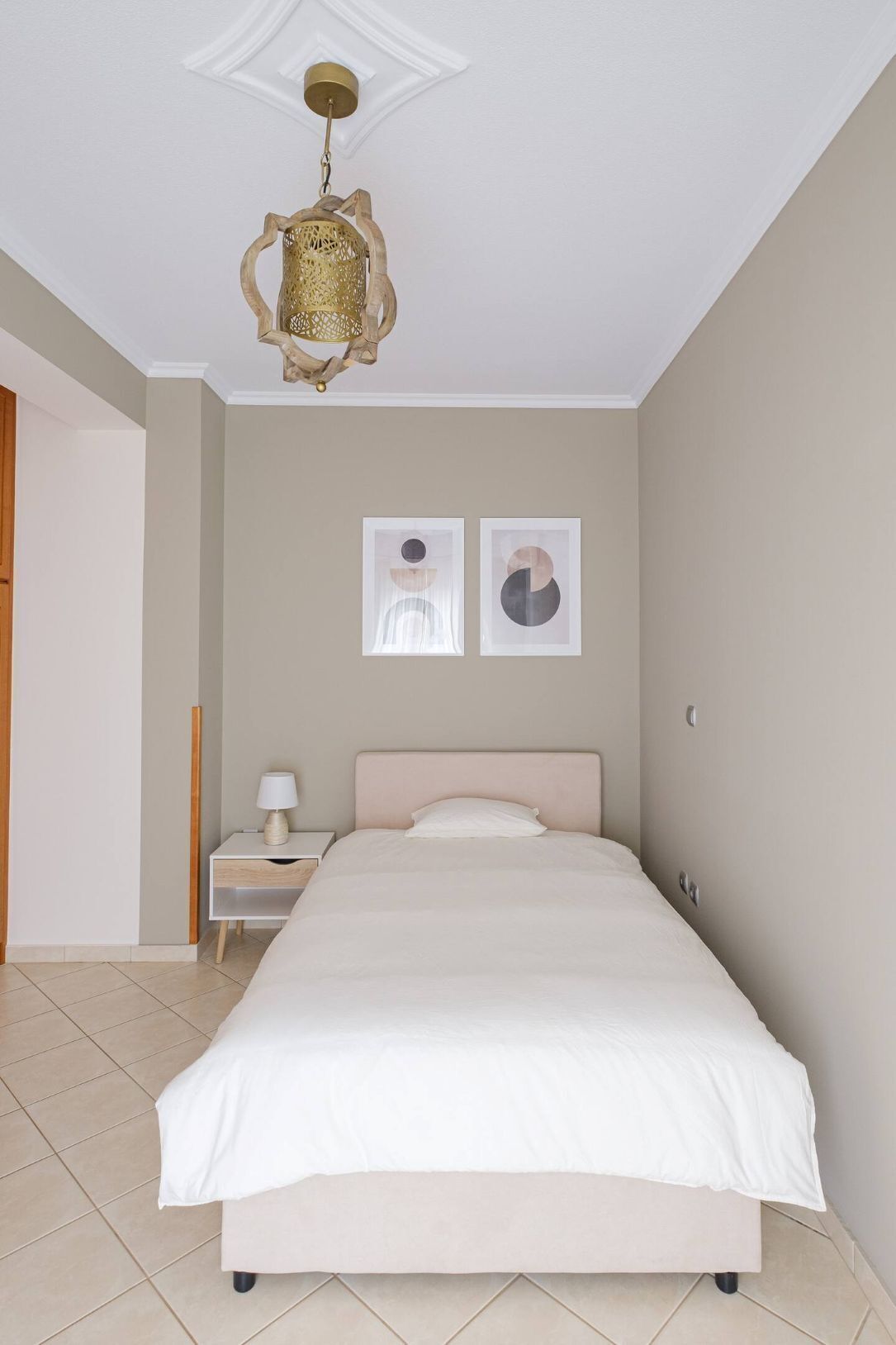 A bedroom with a bed, a nightstand, a lamp, and two wall art pieces.