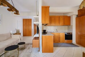 Una cocina moderna con armarios de madera, horno integrado y una zona de comedor con sofá y dos mesas redondas.