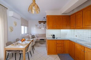 Una cocina con armarios de madera, encimera blanca y un comedor con mesa y sillas.