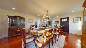A dining room with a wooden table and chairs, a chandelier, and a cabinet. - Spirited Garden- Historic/Central to everything (Galveston)