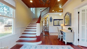 A staircase leading to a second floor, a desk with a lamp, a mirror, and a wall with a sign. - Spirited Garden- Historic/Central to everything (Galveston)
