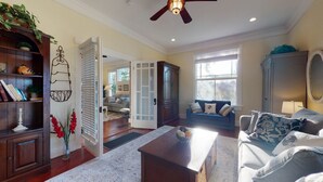 A spacious living room with a fireplace, a dining area, and a view of the outdoors. - Spirited Garden- Historic/Central to everything (Galveston)