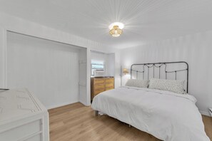 Ein Schlafzimmer mit Bett, Kommode und Deckenleuchte.