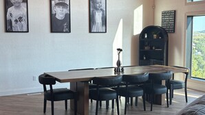 Ruokailutilassa on puinen pöytä ja mustat tuolit, seinällä on kehystettyjä valokuvia ja katosta roikkuu koristeellinen kattokruunu.