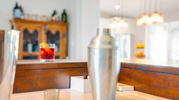 A bar area with a cocktail glass, a metal shaker, and a wooden counter.