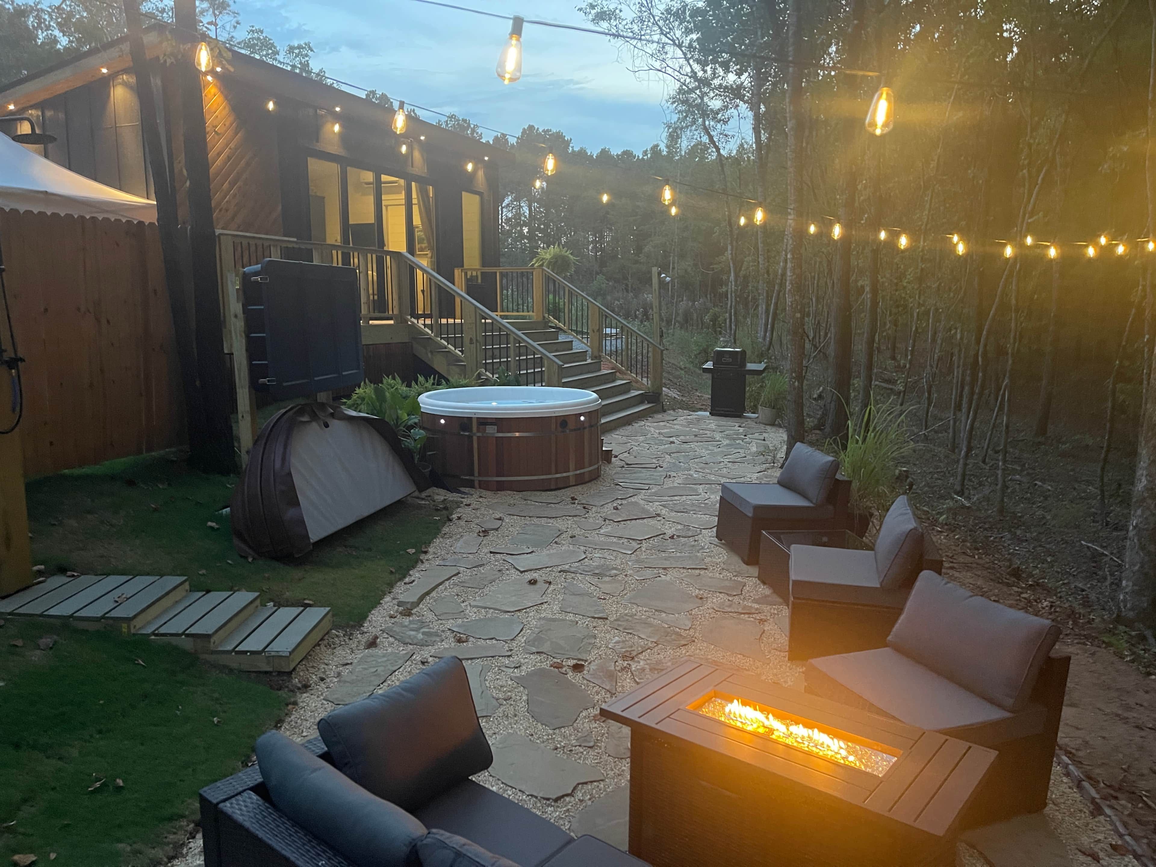 Un jardin avec un jacuzzi, un espace salon extérieur, un escalier et des guirlandes lumineuses.