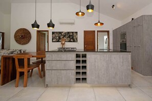 A modern kitchen with a central island, pendant lighting, and a dining area with wooden furniture. - Villa Arc-en-ciel de Vie – Private Pool in Grand B (Rivière du Rempart District)