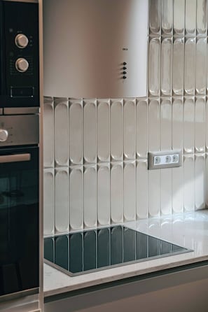 A kitchen with a white tiled backsplash, a built-in oven, and a stainless steel range hood. - Chios Comfort Home D2 (Chios)