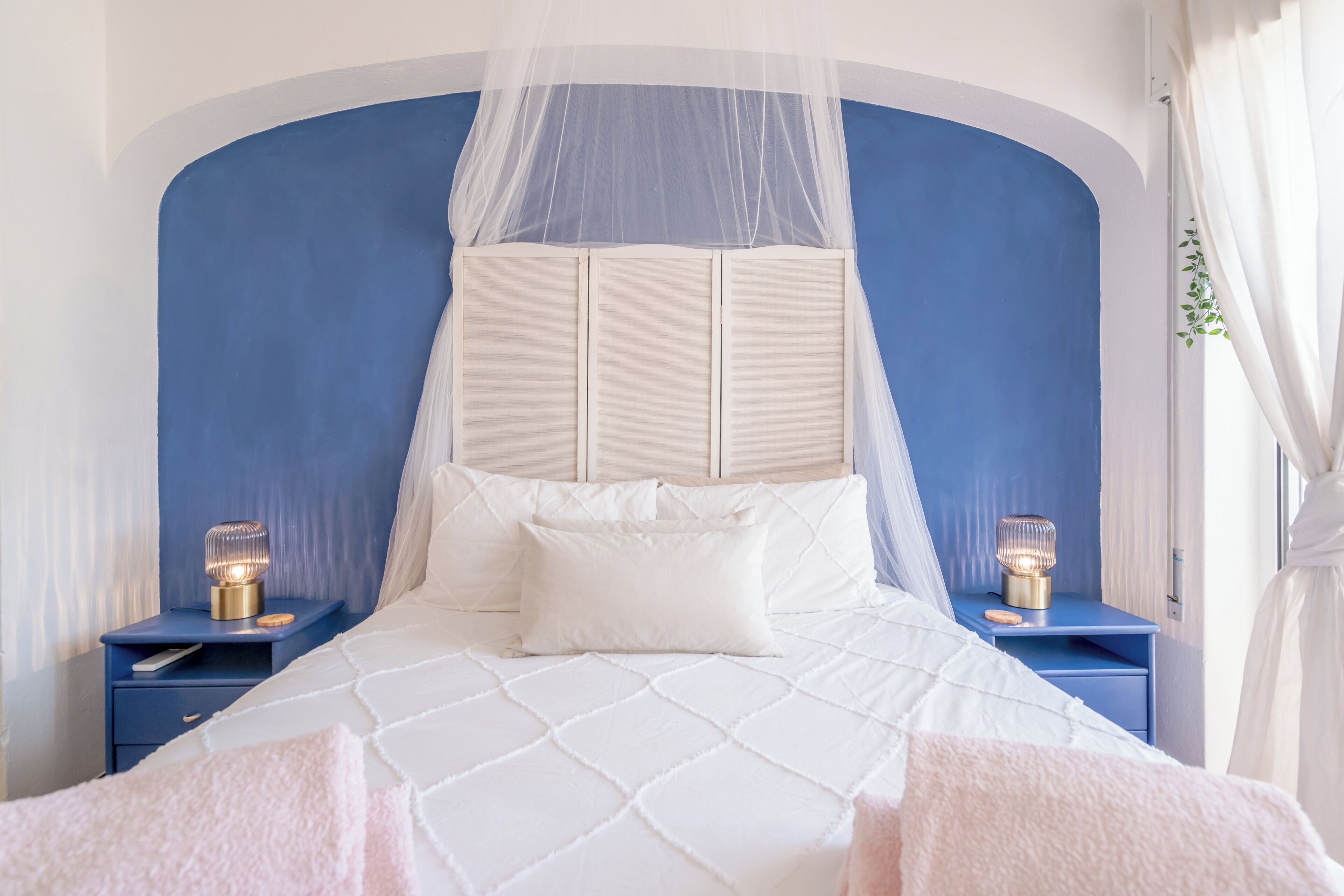 Une chambre à coucher avec un lit à baldaquin, des lampes de chevet et un mur d’accent bleu.