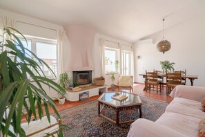 A living room with a fireplace, a dining table, and a sofa. - Boho Beach House, artist residence, steps from the sand (Luz)