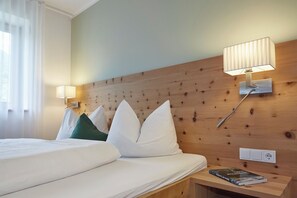 Ein Hotelzimmer mit einem hölzernen Kopfteil, einem Bett mit weißer Bettwäsche, zwei Nachttischlampen und einem Nachttisch mit einem Buch.