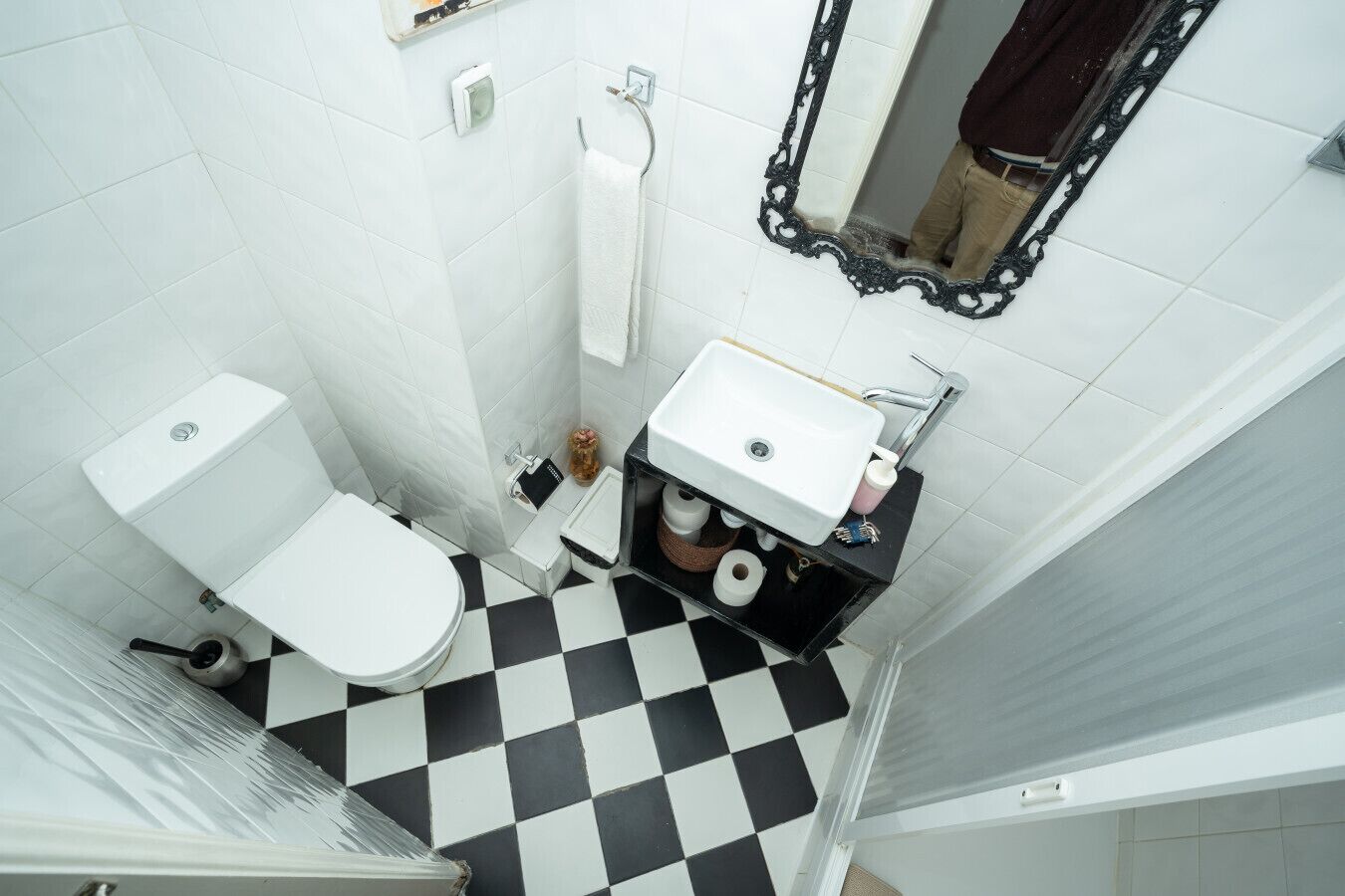 A bathroom with a toilet, sink, and a mirror.