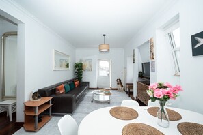 Ein modernes Wohnzimmer mit Sofa, Couchtisch und Essbereich, inklusive Blumenvase.
