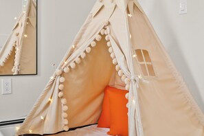 Um quarto aconchegante, tipo tenda, com cama, almofadas e luzinhas.