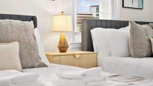 A hotel room with a bed, a nightstand with a lamp, and a window with blinds.