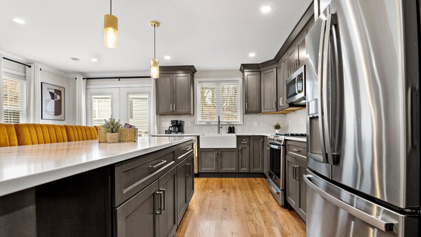 A modern kitchen with stainless steel appliances, wooden flooring, and a central island.