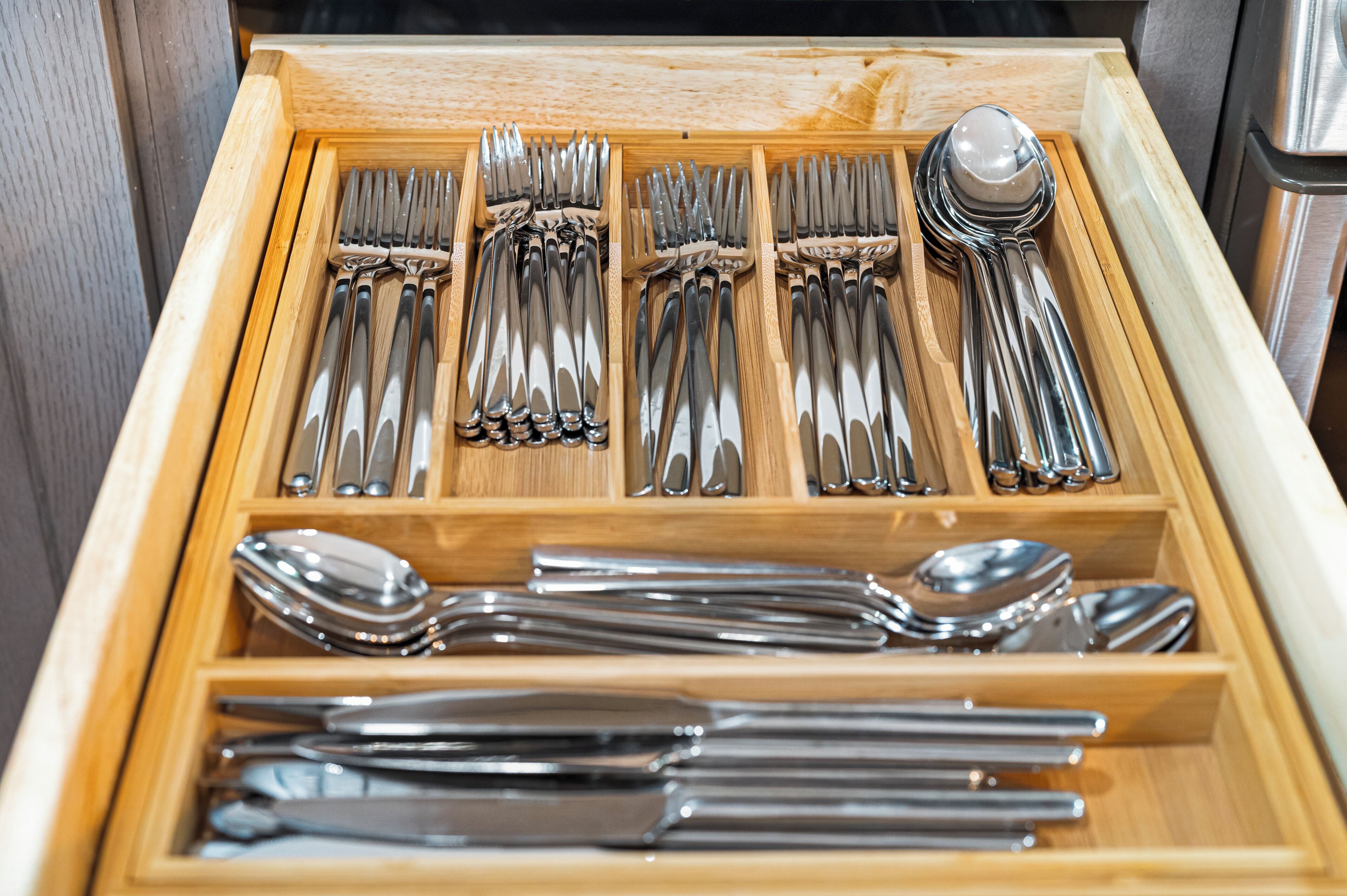 A drawer with neatly organized silverware including forks, knives, and spoons.