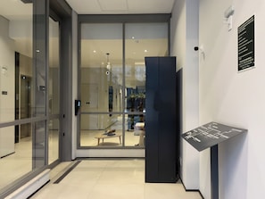En moderne hotellobby med en glasdør, en receptionsdisk og et skilt med nødprocedurer.